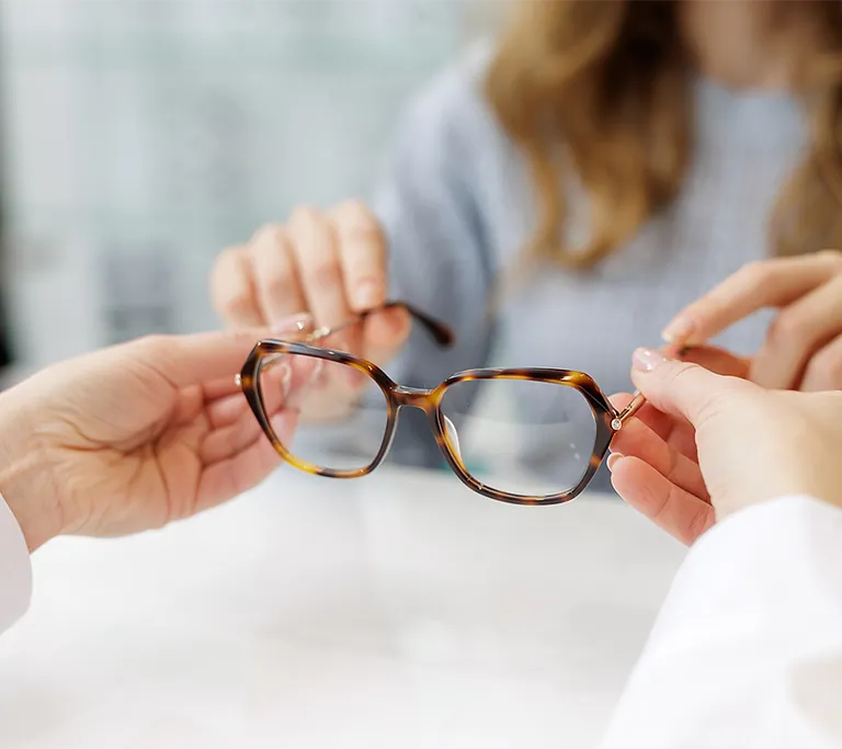 Optikerin die dem Kunden eine Brille übergibt
